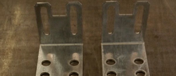 A pair of punched angle brackets made from galvanised steel