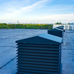 A group of A Series grey painted natural ventilation louvred turrets in-situ on a roof in Manchester