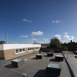 A group of a natural ventilation louvre rooflight turrets painted grey and installed into a school in London